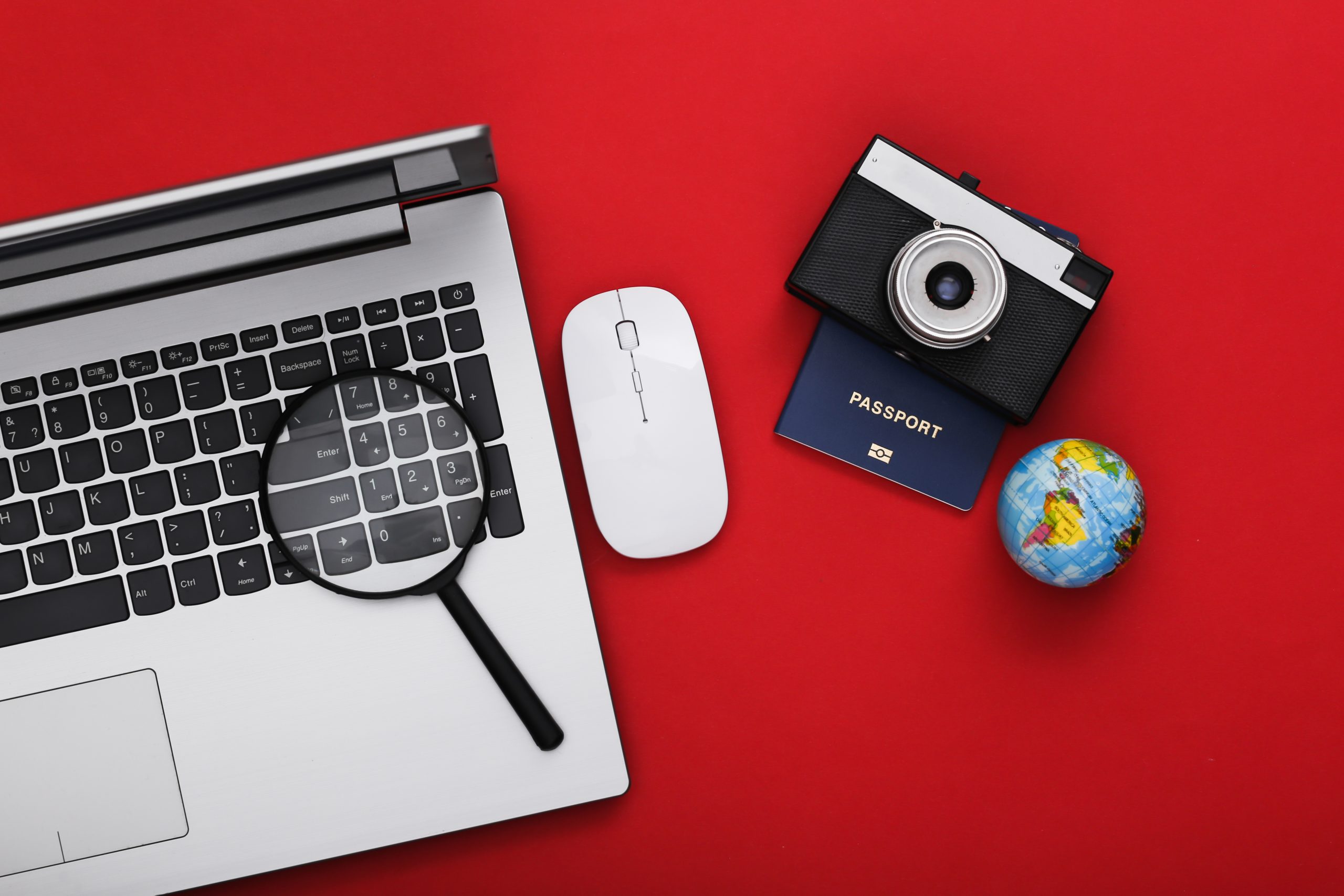Flat lay composition of laptop and travel accessories on red background. Tourism. Top view.